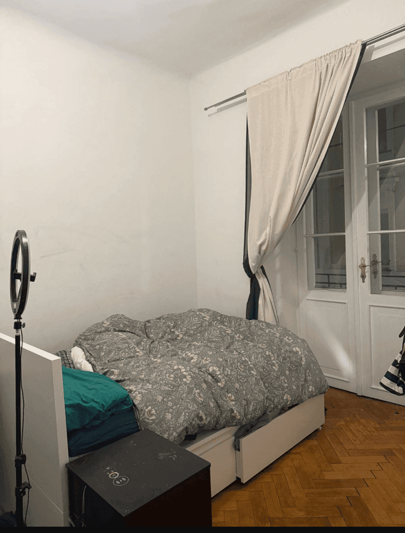 Gemütliches Schlafzimmer mit Einzelbett, Holzboden und Zugang zu einem französischen Balkon.
