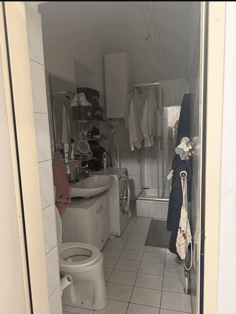 Funktionales Badezimmer mit Waschbecken, Toilette, Dusche und Waschmaschine.