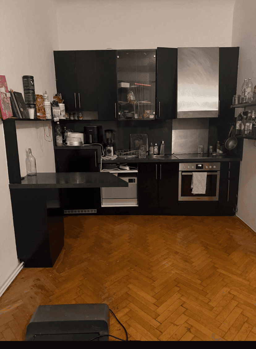 Voll ausgestattete Küche mit schwarzen Schränken, Herd und Mikrowelle, ideal für kleine Räume.