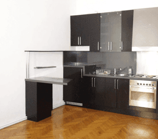 Moderne Einbauküche mit dunklen Schränken, integriertem Backofen und Holzboden.