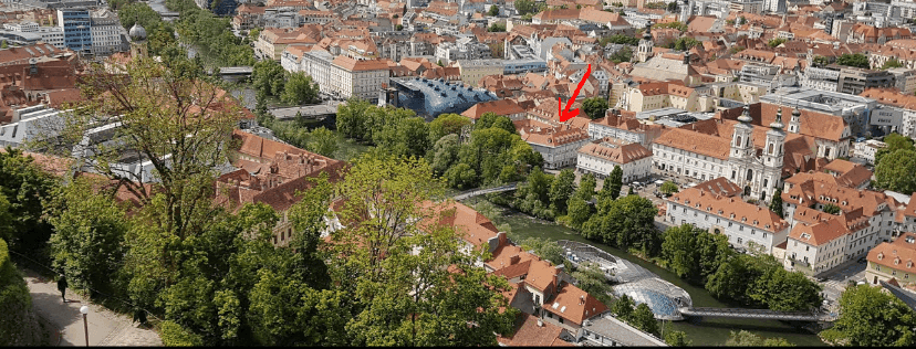 Panoramablick über eine historische Stadt mit Fluss, Gebäuden und grünen Ufern.
