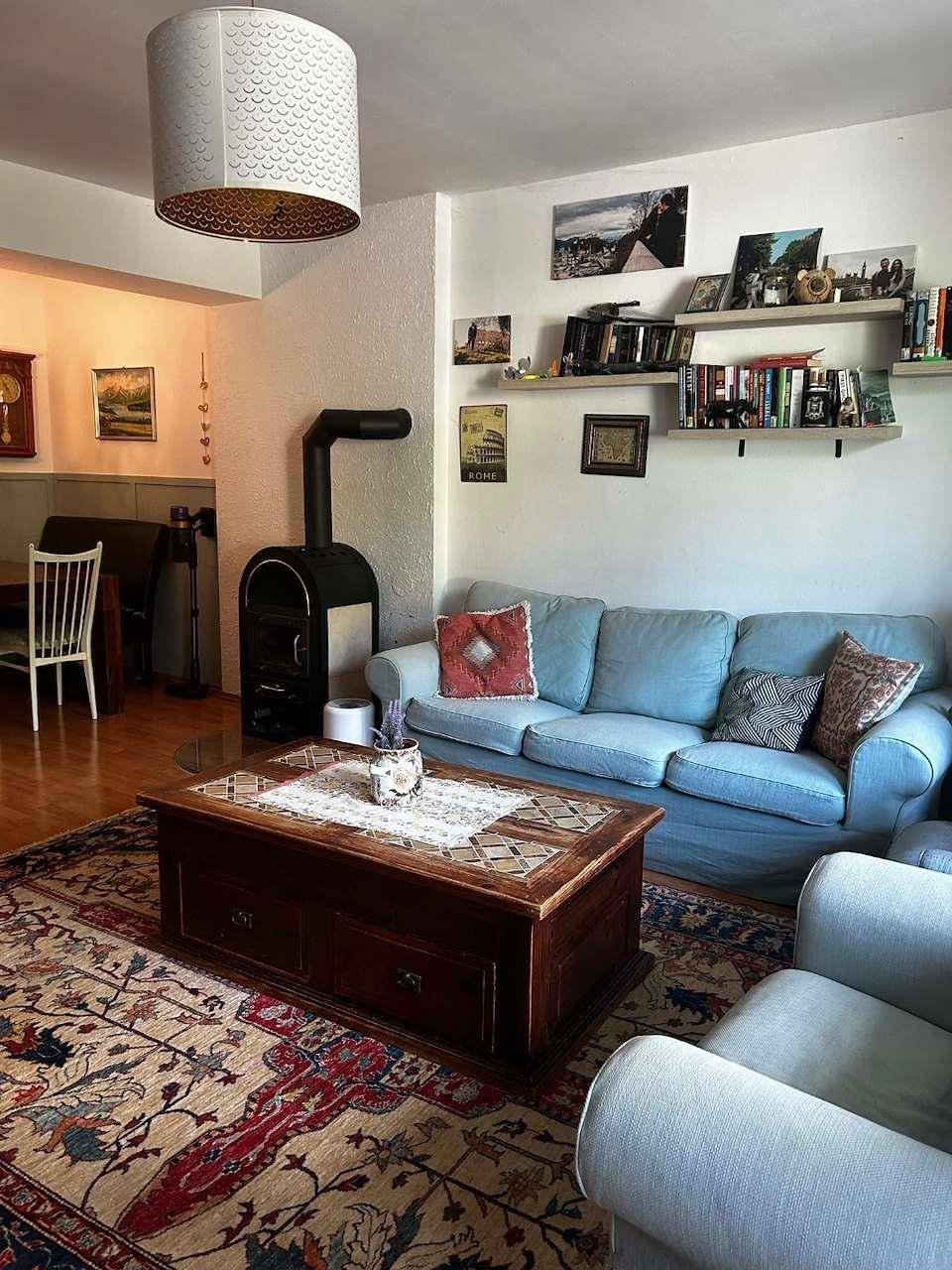 Wohnzimmer mit hellem Sofa, Kaminofen und Teppich, gemütlich und individuell eingerichtet.
