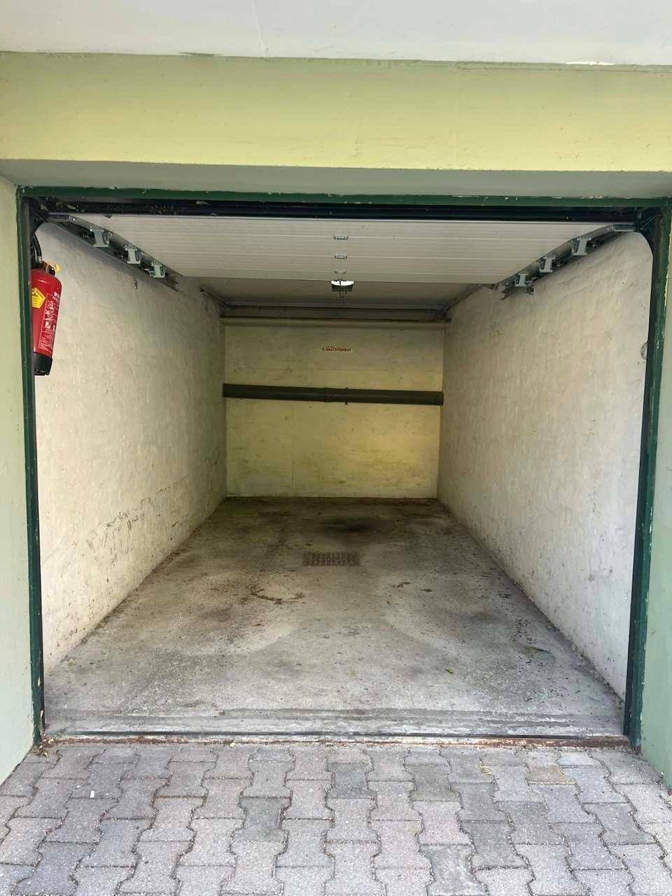 Leere Garage mit Betonboden und weiß gestrichenen Wänden, bereit zur Nutzung.