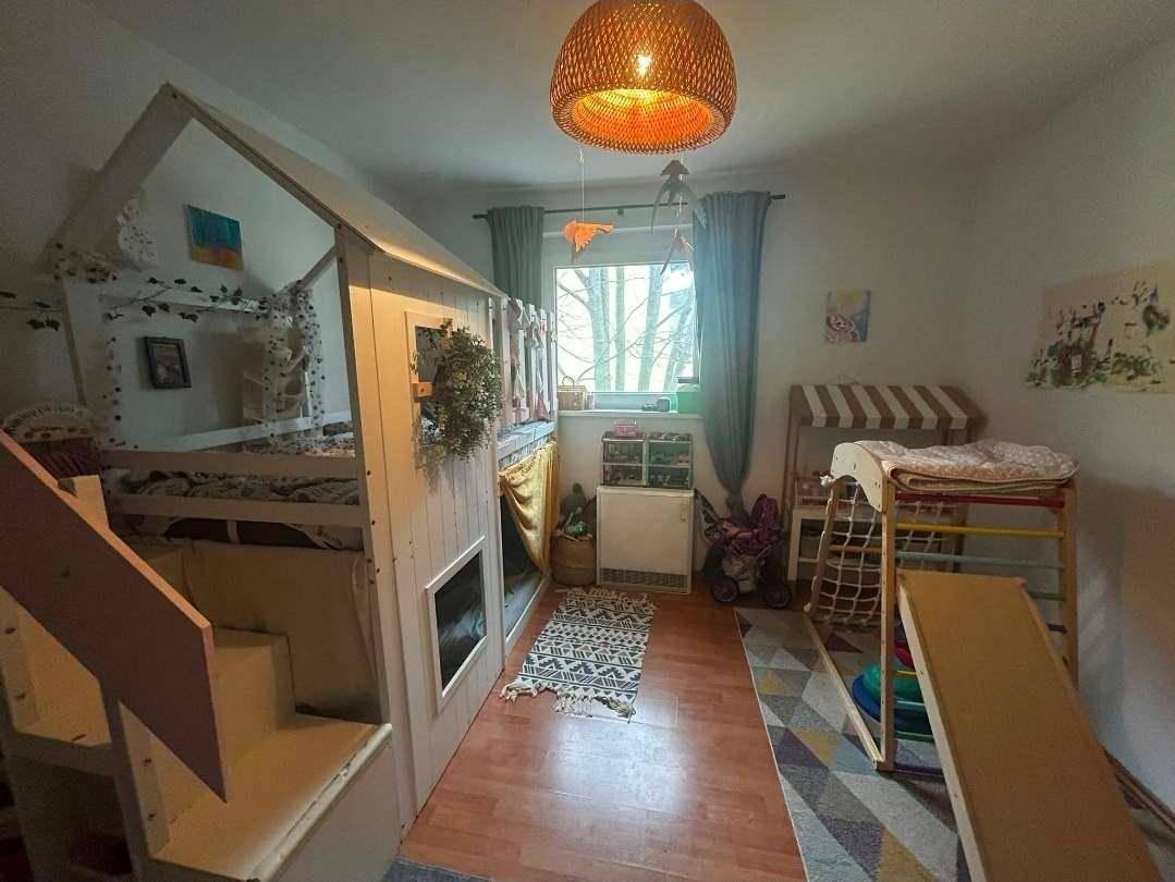 Helles Kinderzimmer mit Spielbett, Rutsche und Fenster, ideal zum Spielen und Schlafen.