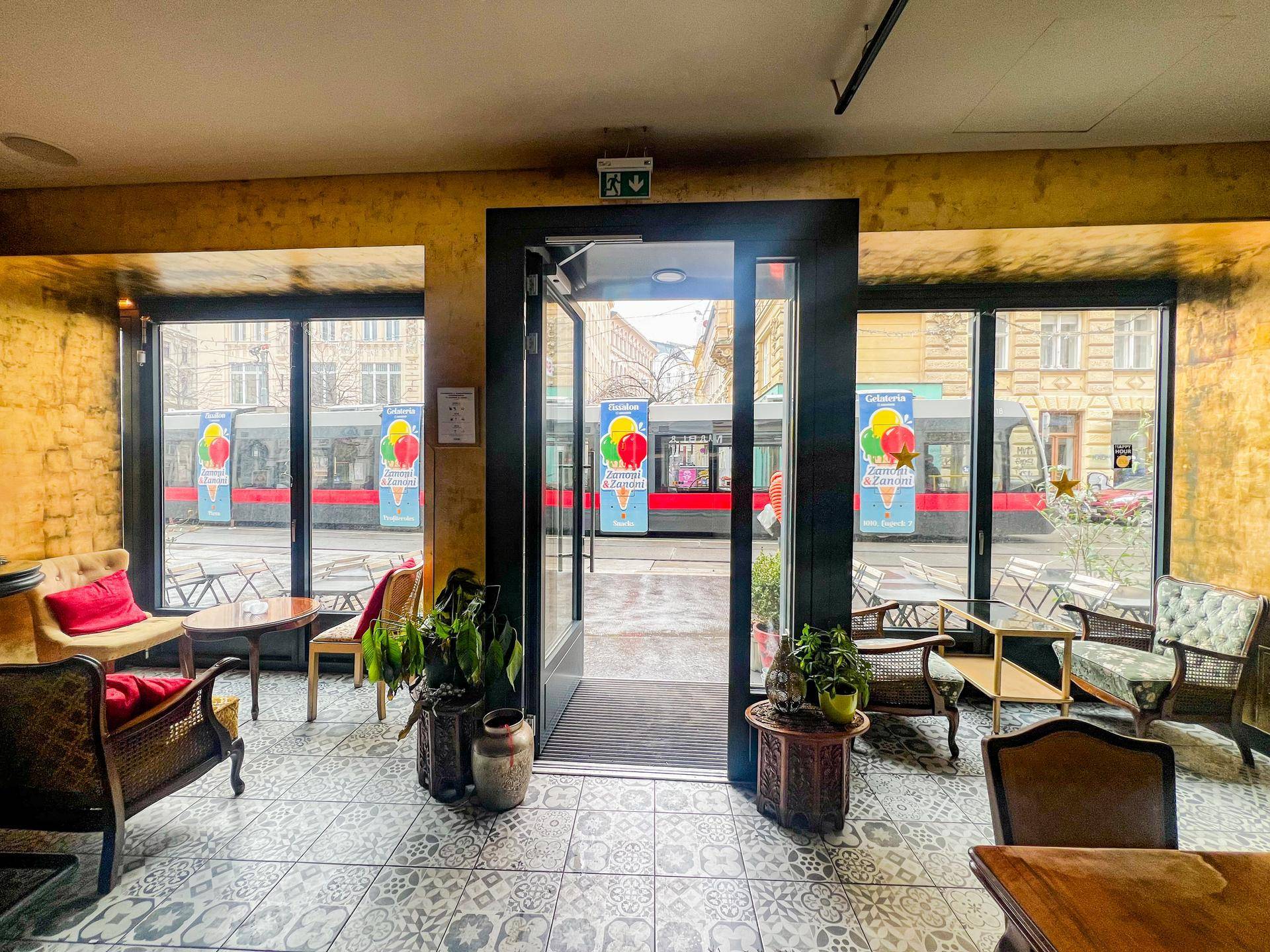 Heller Sitzbereich mit großen Fenstern, die einen Blick auf die belebte Straße und eine Straßenbahn bieten.