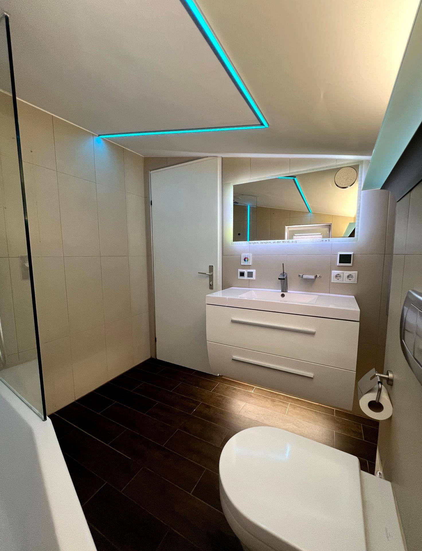 Modernes Badezimmer mit Waschtisch, WC und indirekter Beleuchtung.