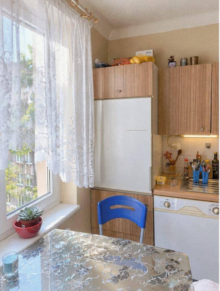 Helle Küche mit Esstisch, Kühlschrank und Fenster, das einen grünen Ausblick bietet.