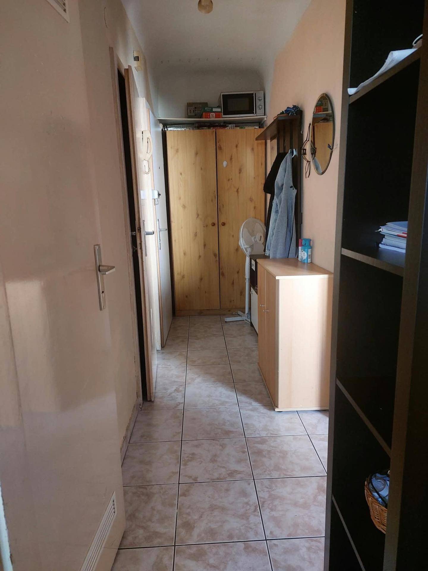 Langer Flur mit Fliesenboden, Holzschrank und Blick auf weitere Räume im Haus.