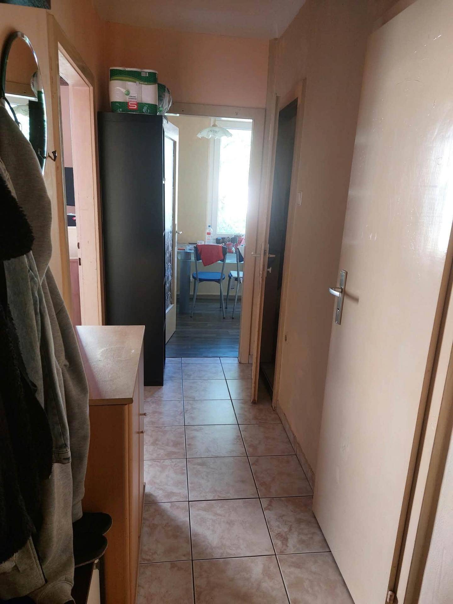 Flur mit Fliesenboden und Garderobe, der zu einem hellen Essbereich führt.