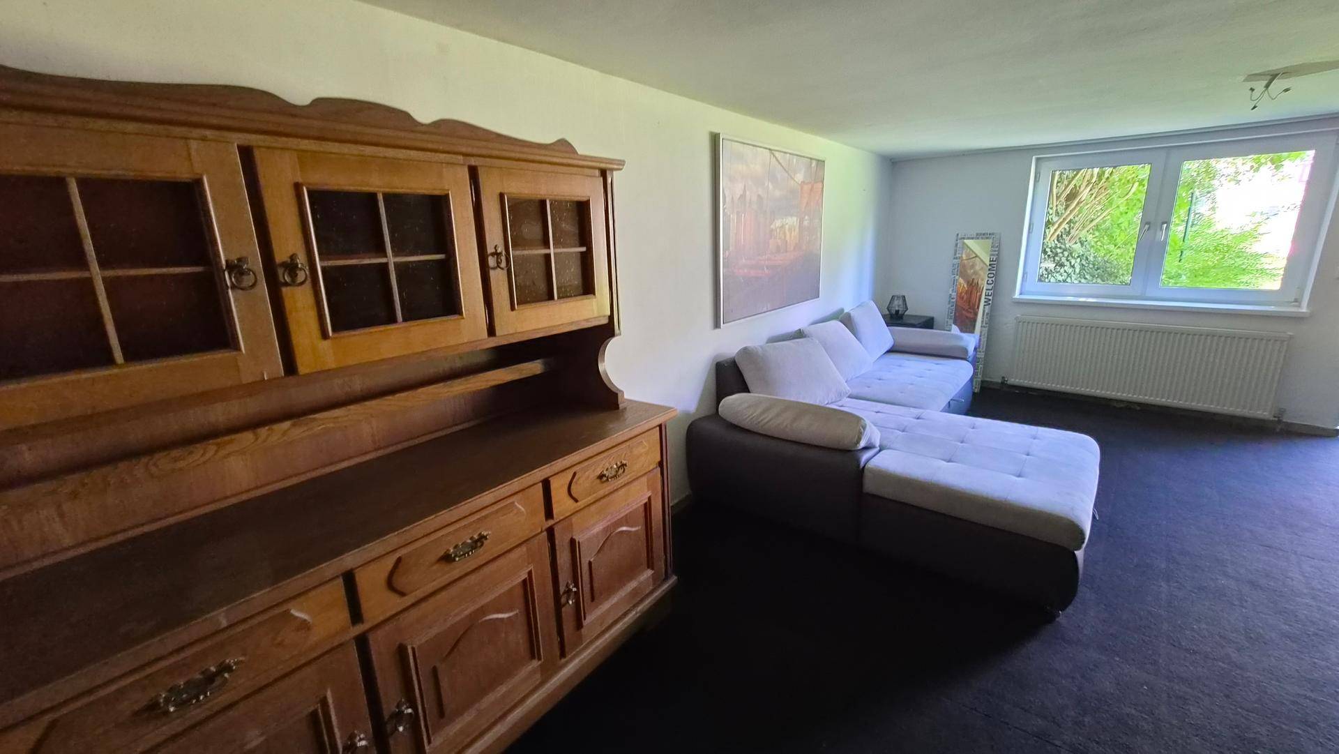 Kellerraum mit Teppichboden, Sofa und traditionellem Holzschrank.