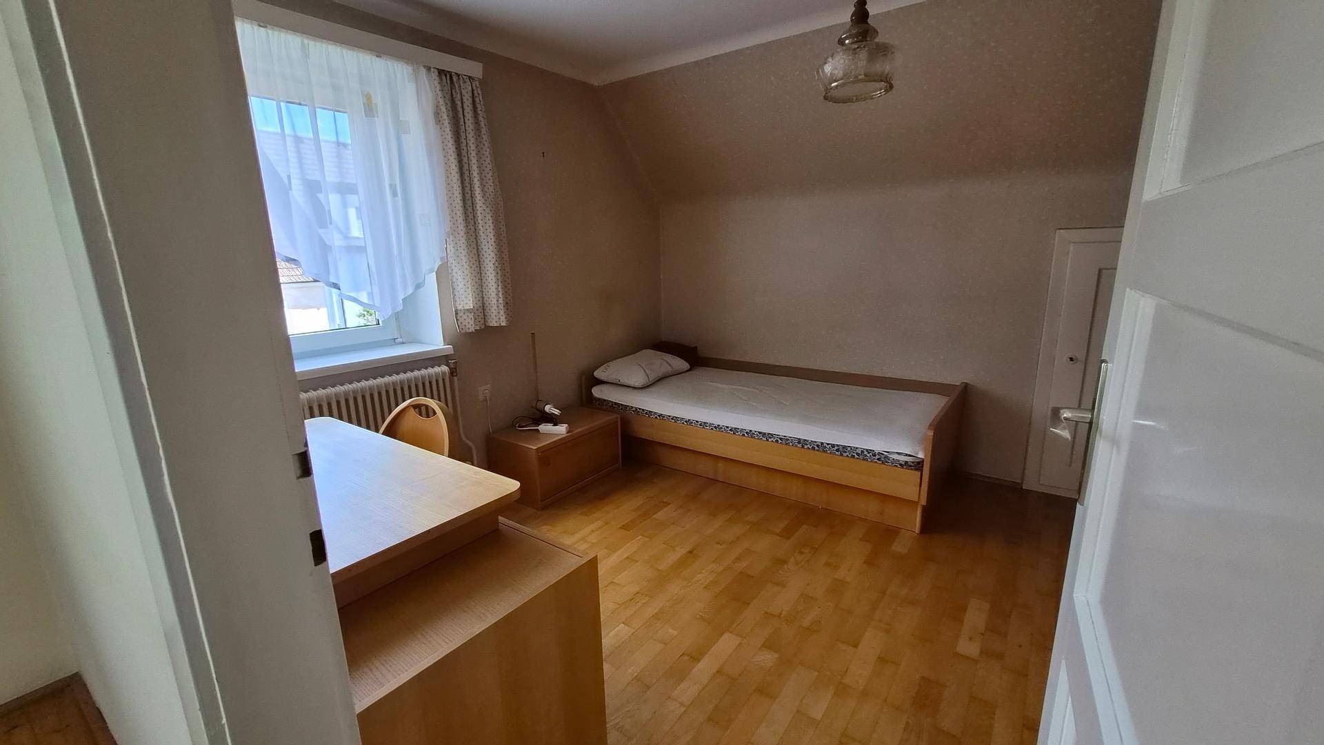 Schlafzimmer im Dachgeschoss mit Einzelbett, Schreibtisch und schräger Decke.