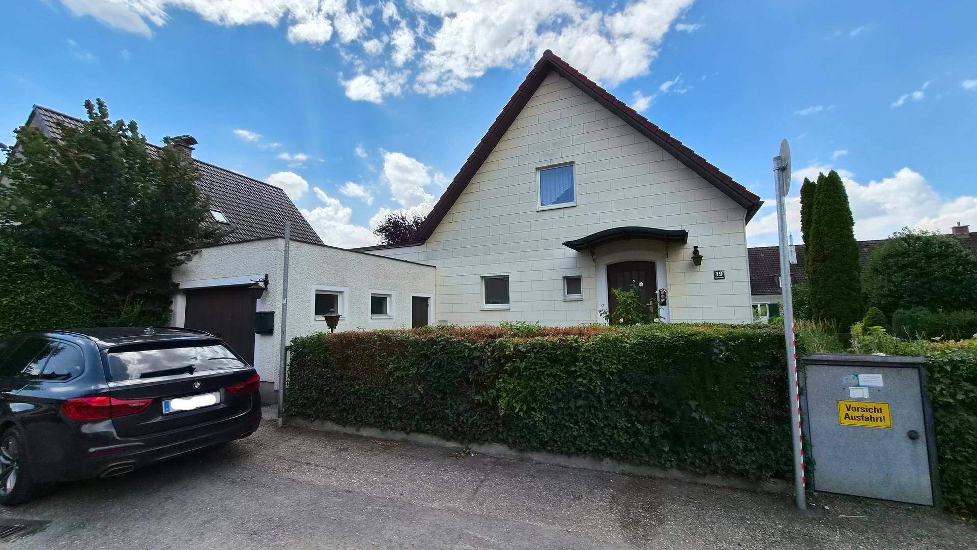 Vorderansicht des Einfamilienhauses von der Straße aus mit einem gepflegten Vorgarten und Garagenzufahrt.