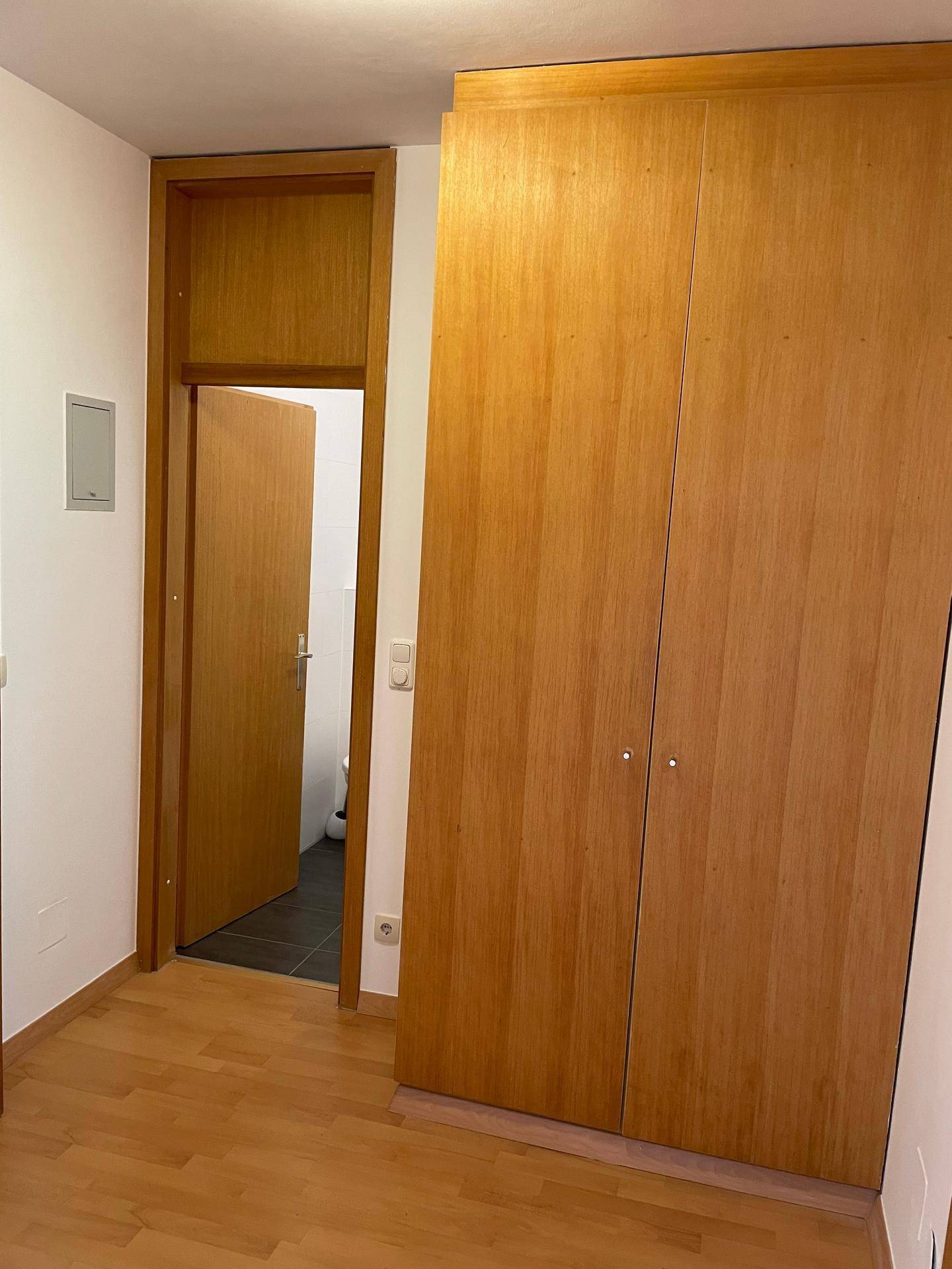 Flur mit einem großen, integrierten Holzschrank und Zugang zu einem angrenzenden Raum.