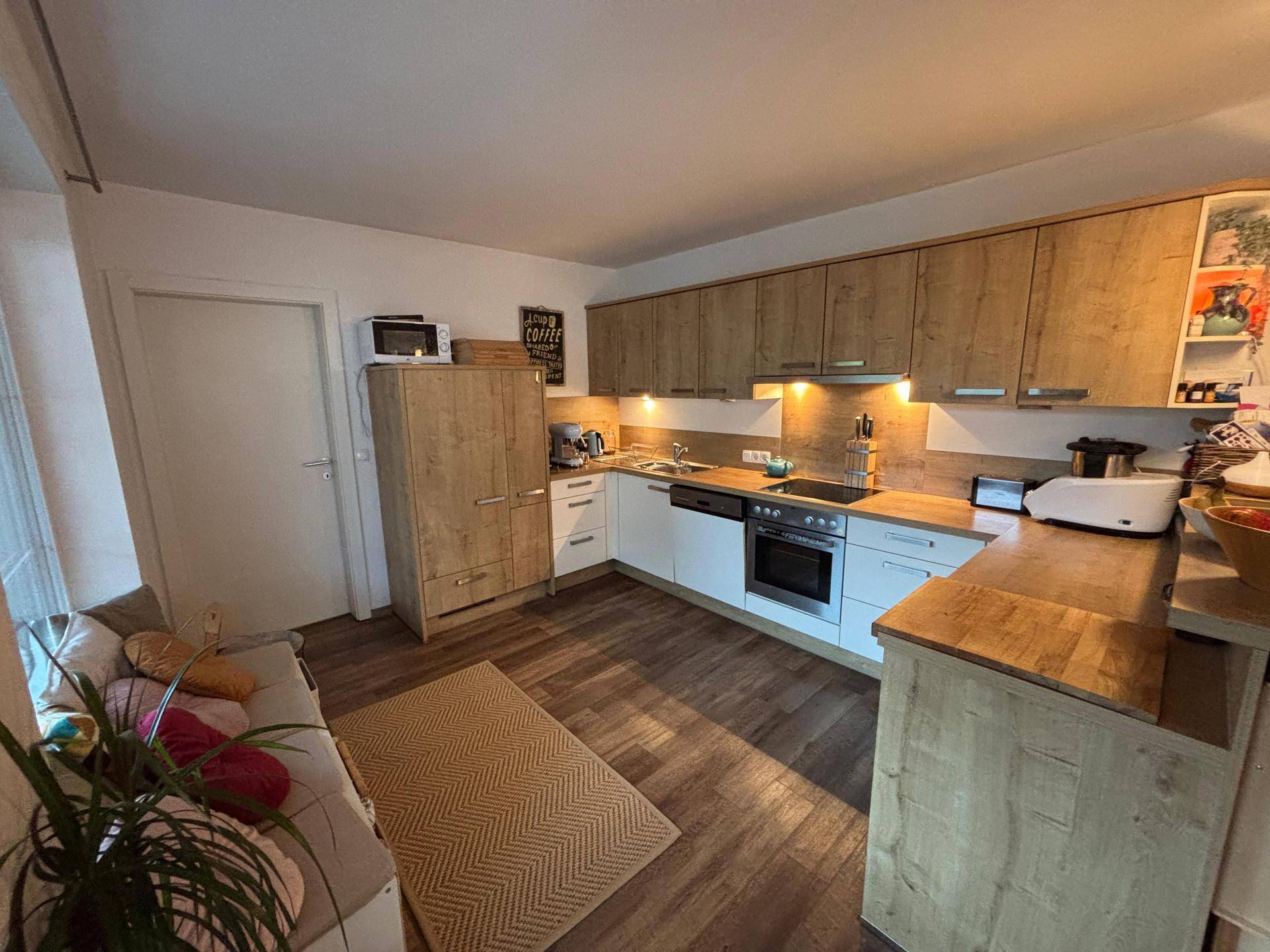 Moderne Küche mit Holzfronten, weißen Unterschränken und integrierten Geräten.