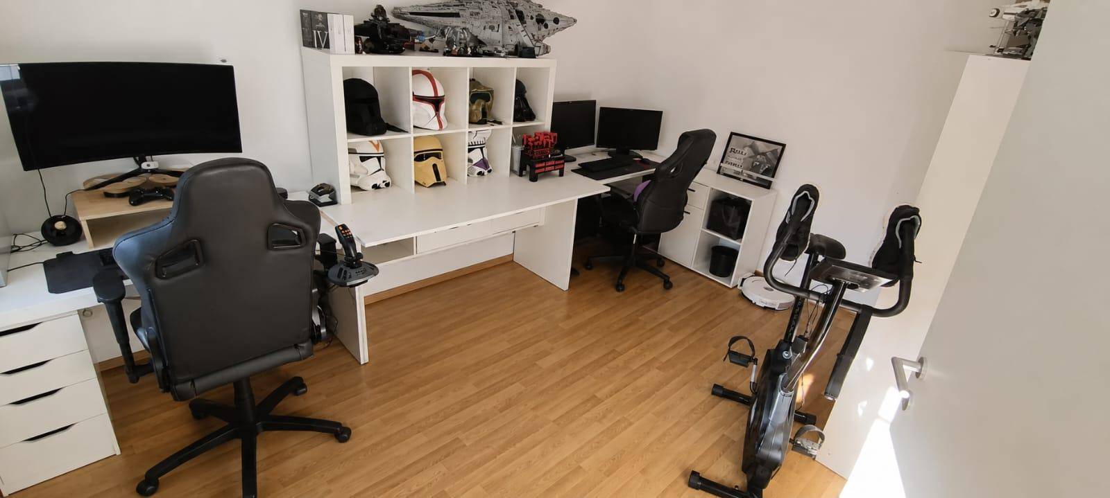 Arbeitszimmer mit zwei Schreibtischen, Regalen und Fitnessgeräten.