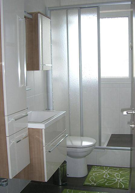 Modernes Badezimmer mit Duschkabine, Toilette, Waschtisch und Fenster für Tageslicht.