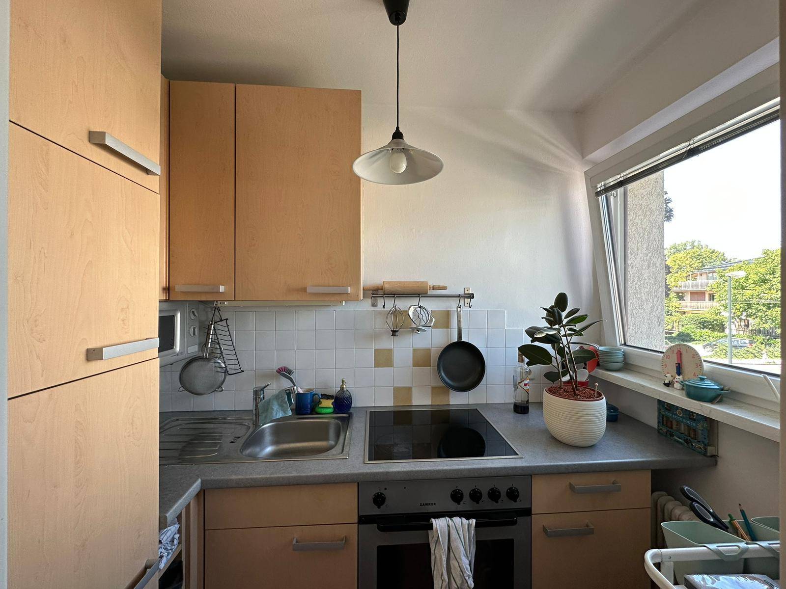 Funktionale Küchenzeile mit Backofen, Spüle und Fenster mit Blick ins Grüne.