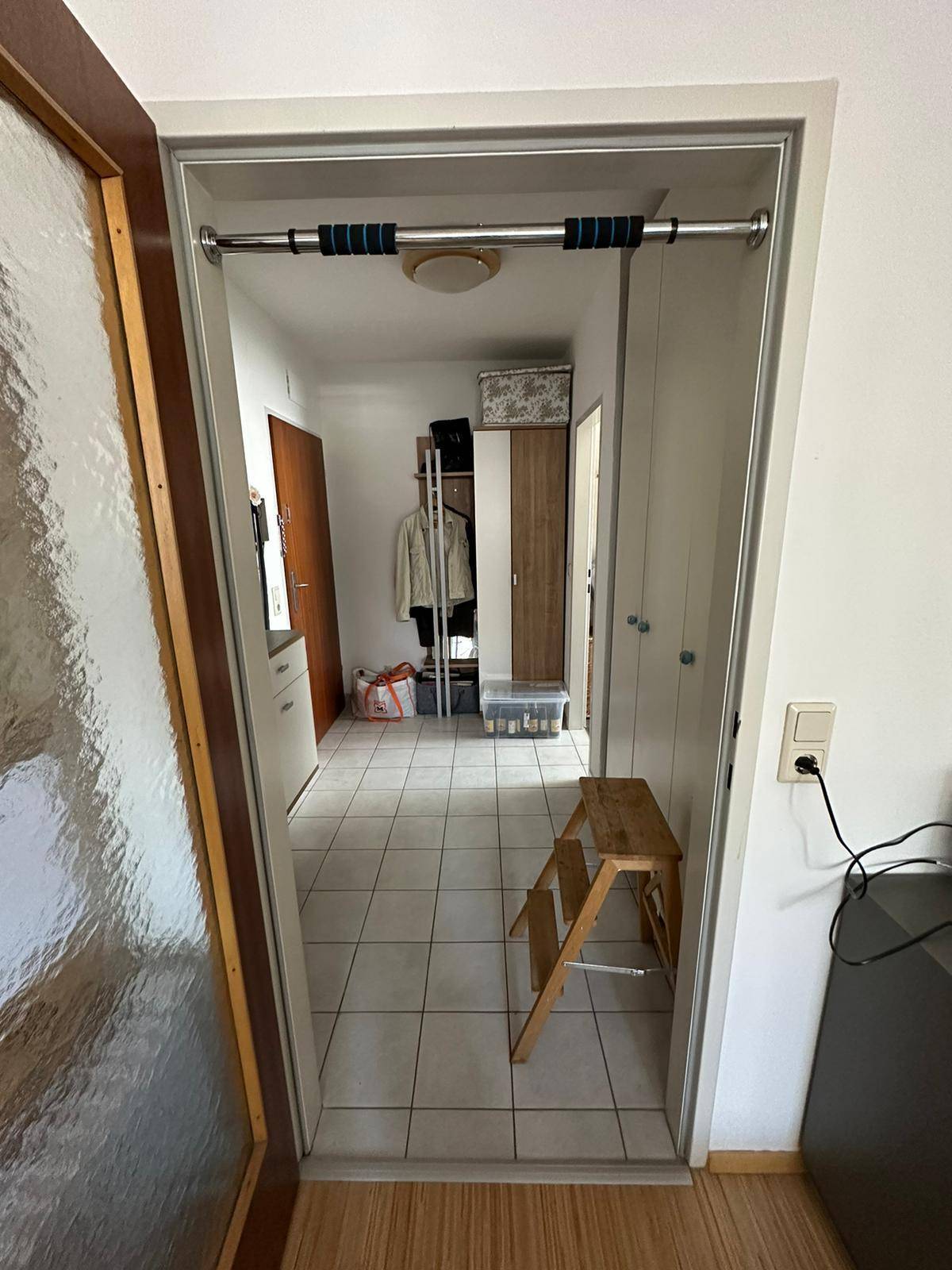 Gefliester Flur mit Durchgang zu weiteren Räumen und einer Klimmzugstange im Türrahmen.