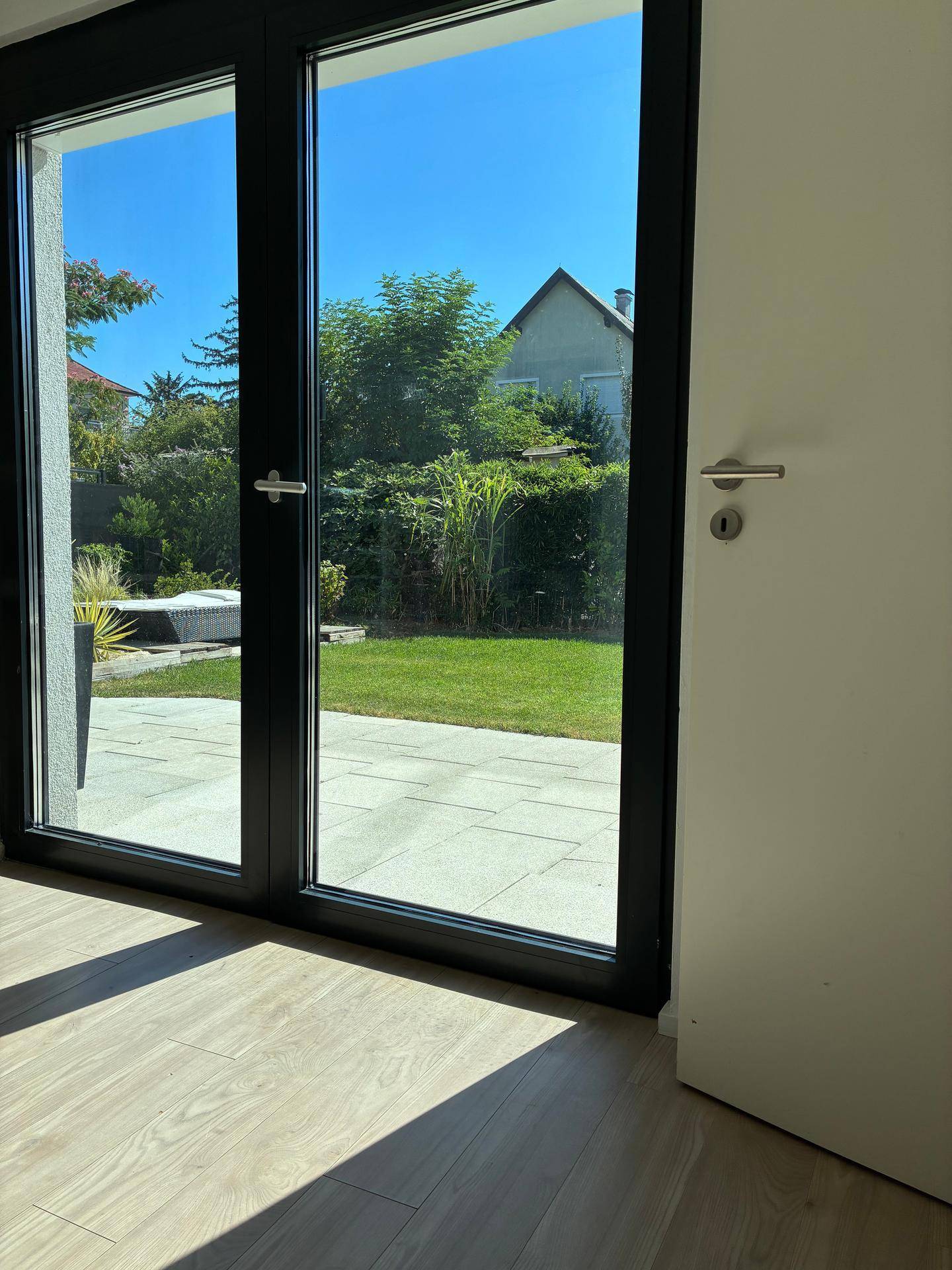 Heller Innenraum mit großen Glastüren, die den Blick auf den Garten und die Terrasse freigeben.