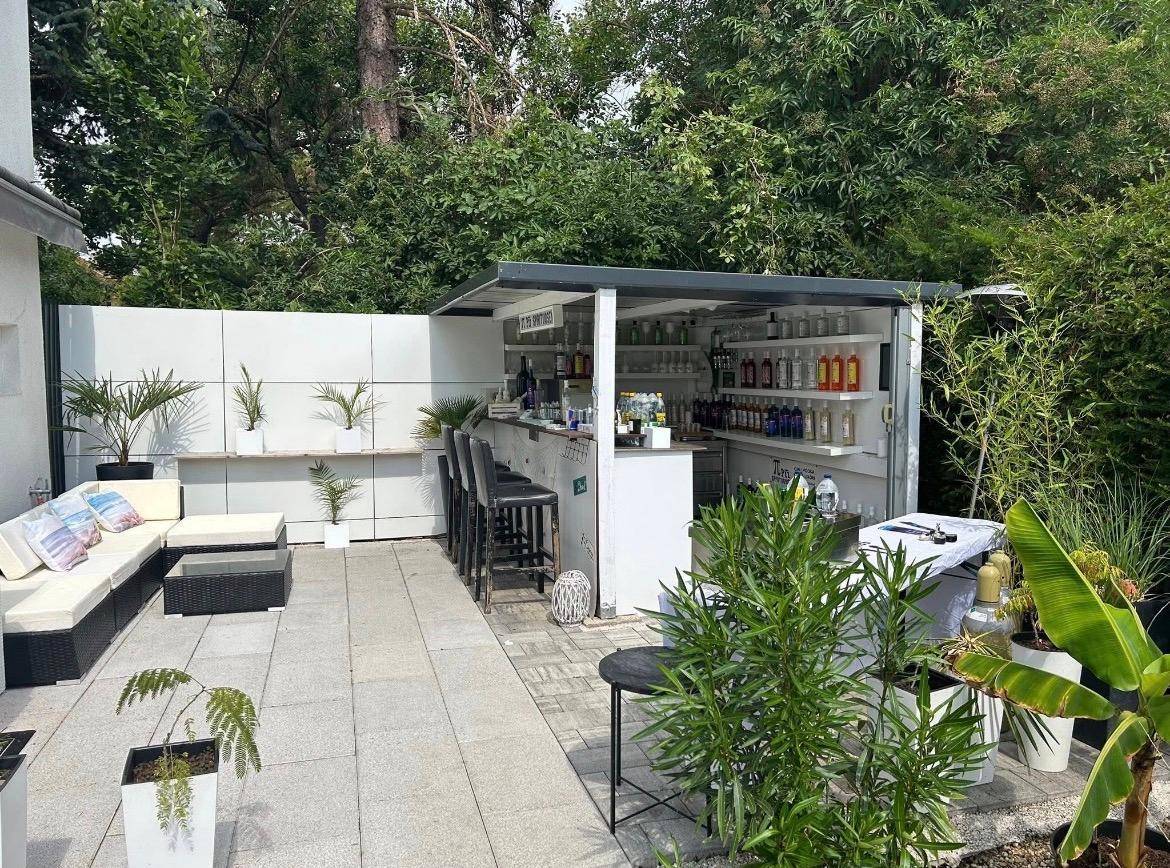 Gemütliche Terrasse mit einer voll ausgestatteten Außenbar, bequemen Loungemöbeln und vielen Pflanzen.