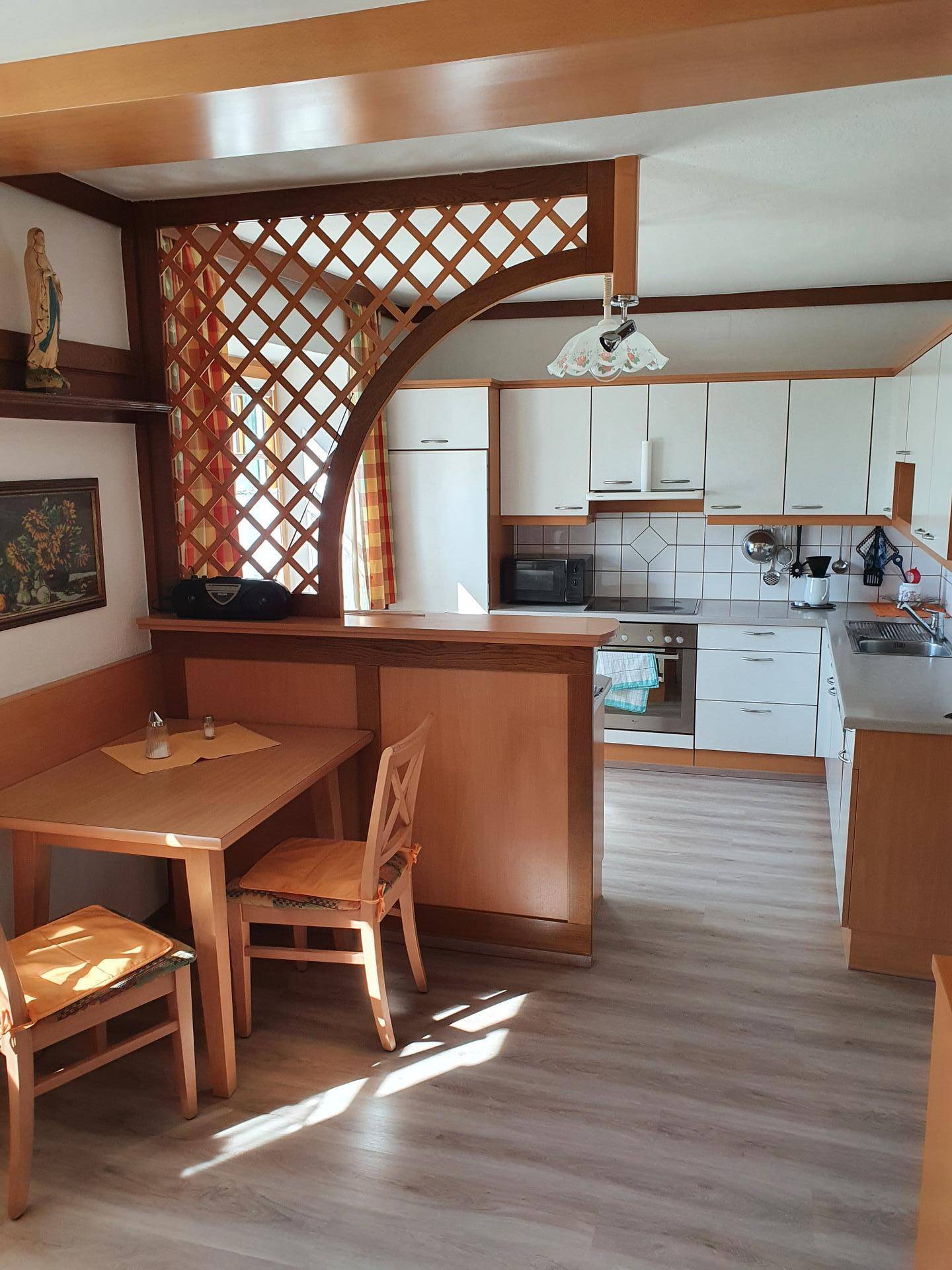Helle Küche mit integriertem Essbereich, Holzdetails und Blick nach draußen.