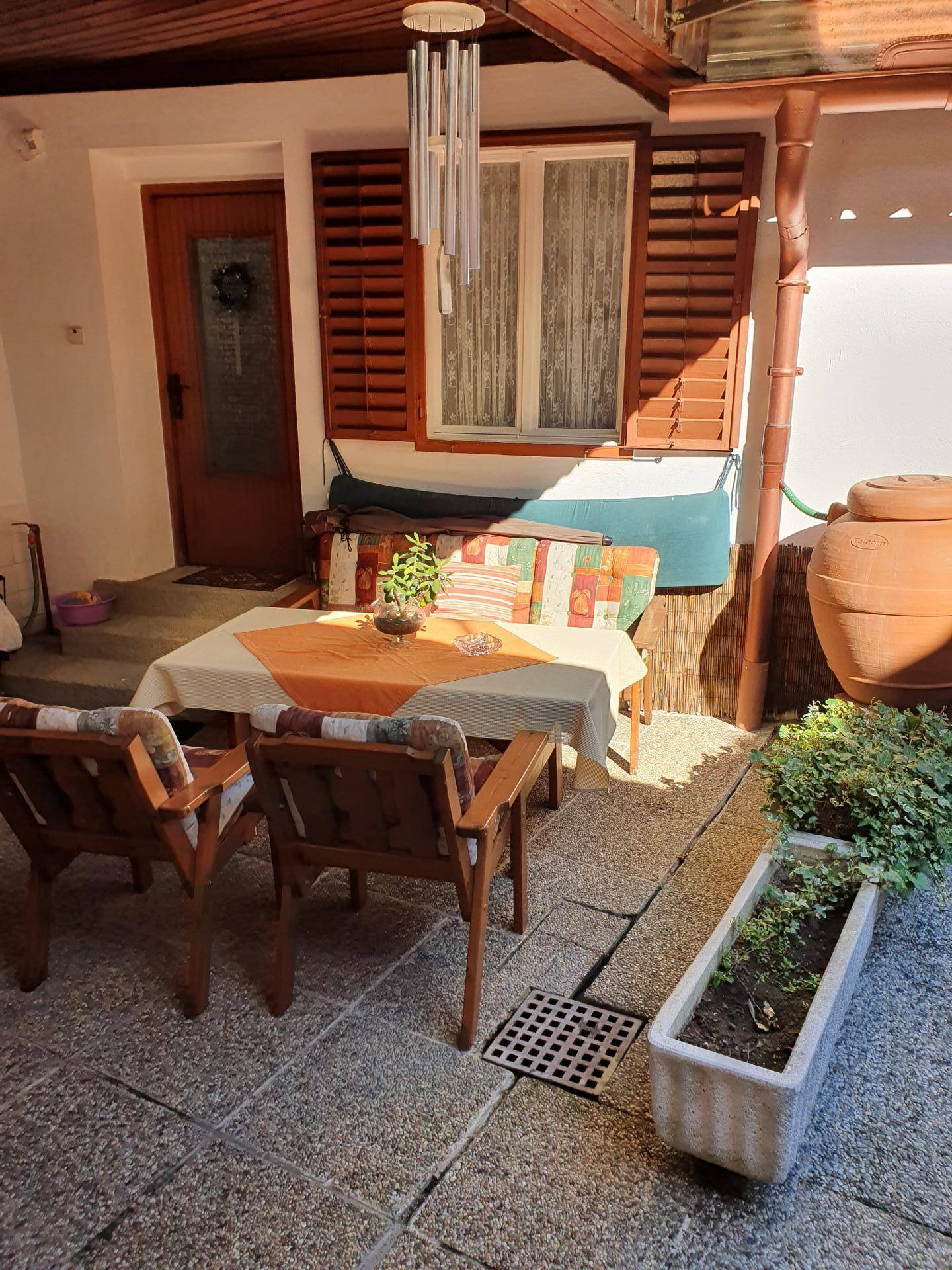 Überdachter Außenbereich im Innenhof mit Sitzgelegenheiten und Steinfliesenboden.