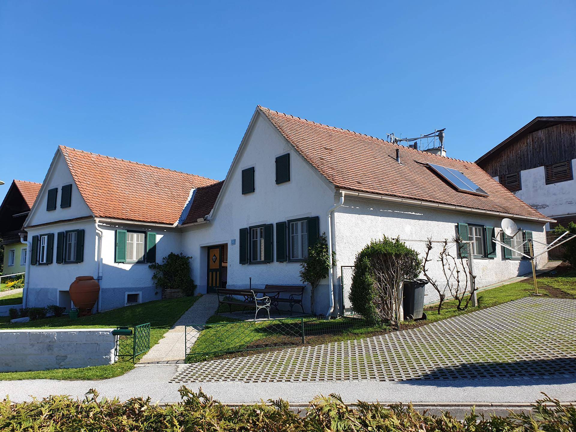 Charmantes Einfamilienhaus mit weißer Fassade, grünen Fensterläden und Solarpaneelen auf dem Dach.