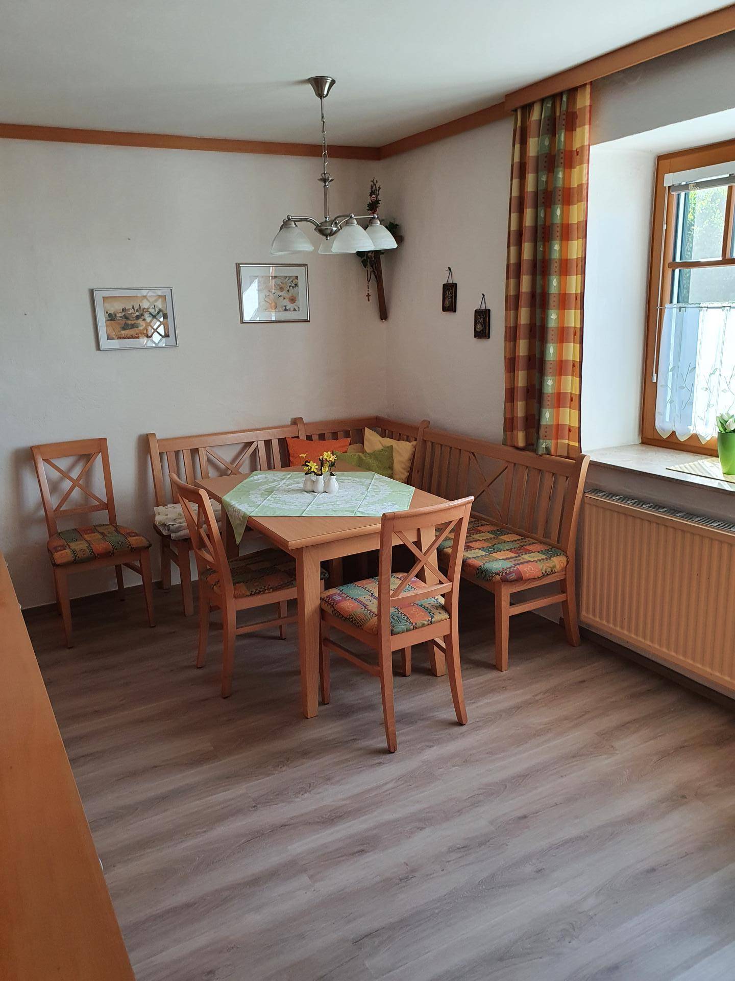 Gemütlicher Essbereich mit Holztisch, Eckbank und Stühlen, beleuchtet durch ein Fenster.