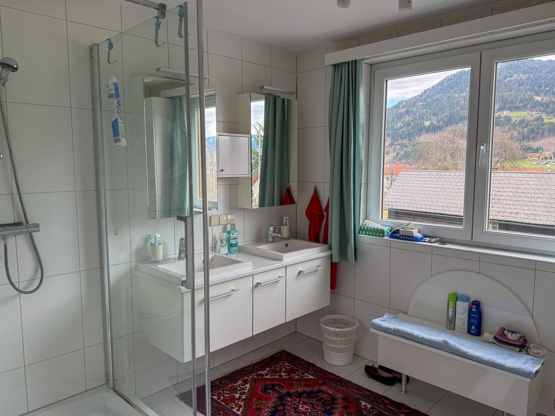 Modernes Badezimmer mit Doppelwaschbecken, großer Dusche und Fenster mit Bergblick.
