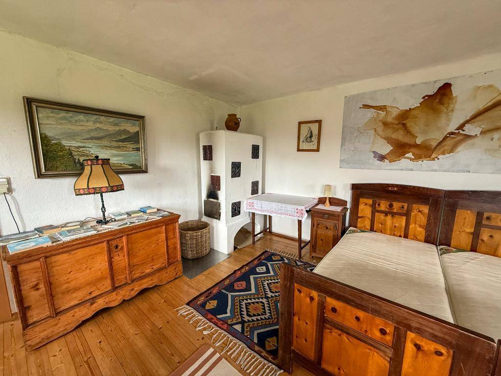 Schlafzimmer mit traditionellem Kachelofen, Holzboden und rustikalen Möbeln, bietet eine gemütliche Atmosphäre.