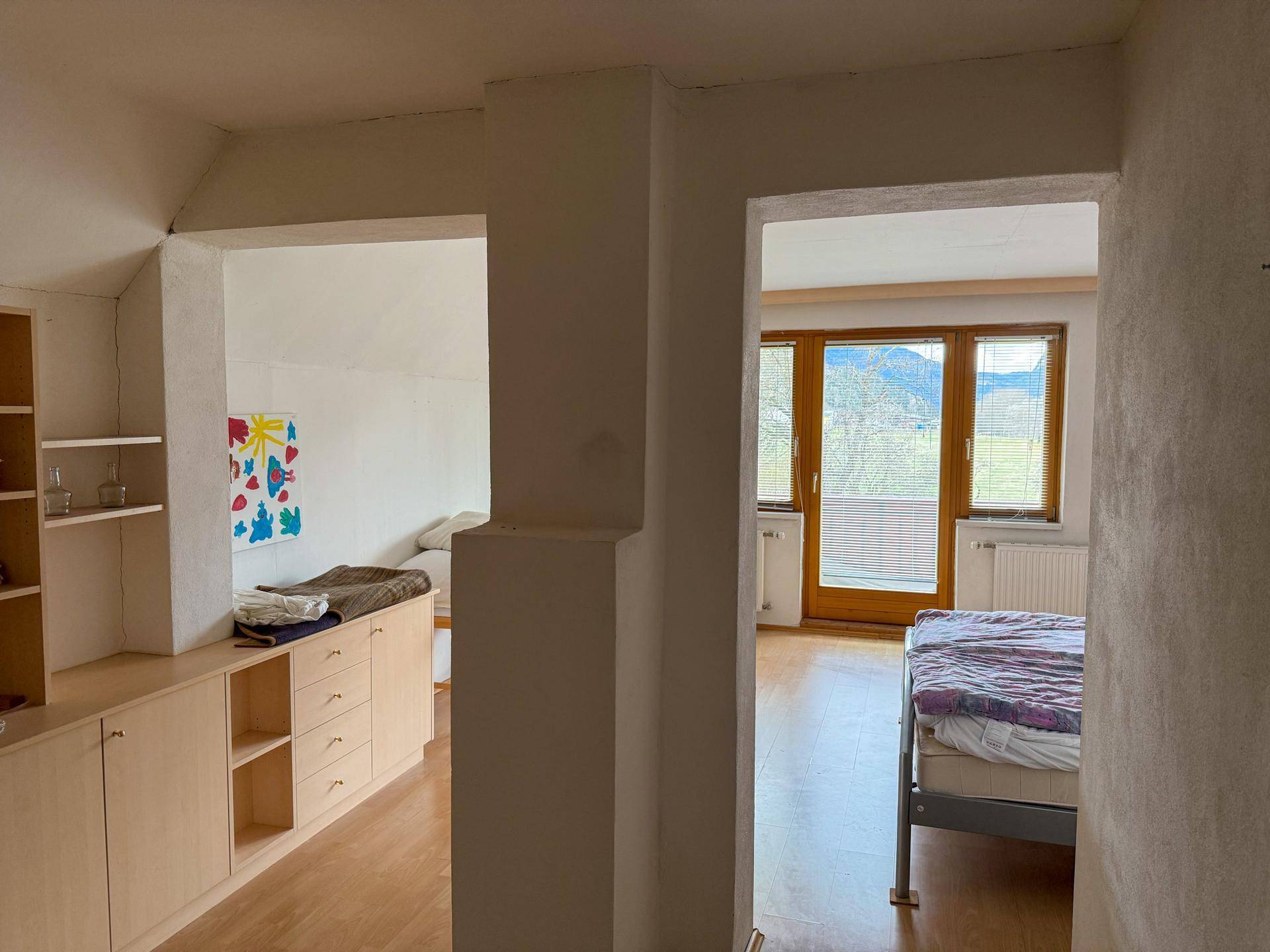 Schlafzimmer mit Holzboden, Einbauschränken und Zugang zu einem Balkon mit Bergblick.