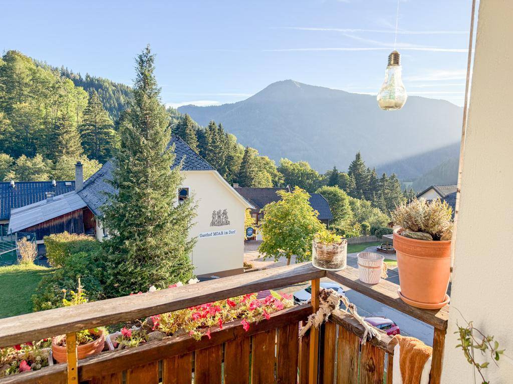 Sonniger Balkon mit Blumenkästen und weitem Blick auf die umliegende Berglandschaft.