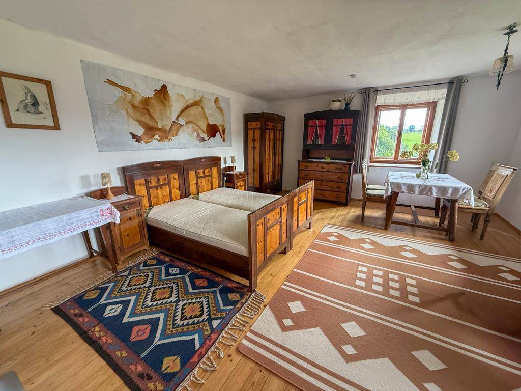 Geräumiges Schlafzimmer mit traditionellen Holzmöbeln, Holzboden und gemusterten Teppichen, hell und einladend.