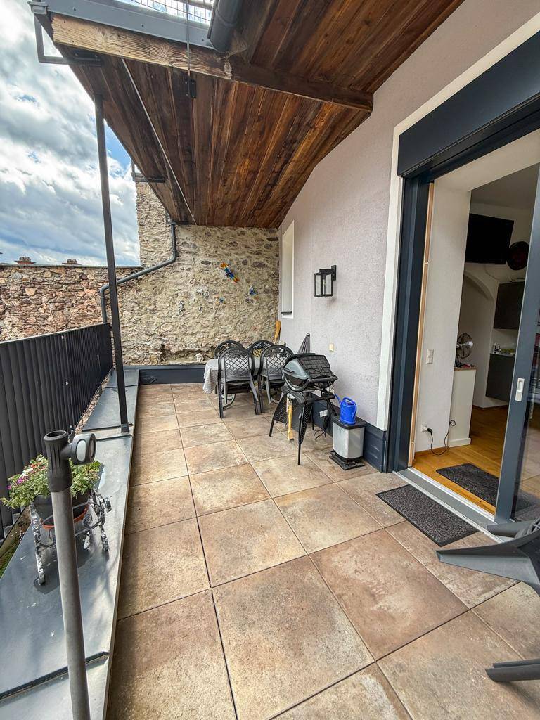Geräumige Terrasse mit Fliesenboden, Sitzgelegenheiten und Grillbereich.