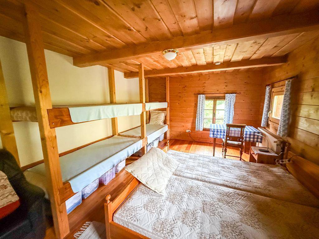 Rustikales Schlafzimmer mit Etagenbetten, Holzwänden und karierten Vorhängen, ideal für Gäste oder Kinder.