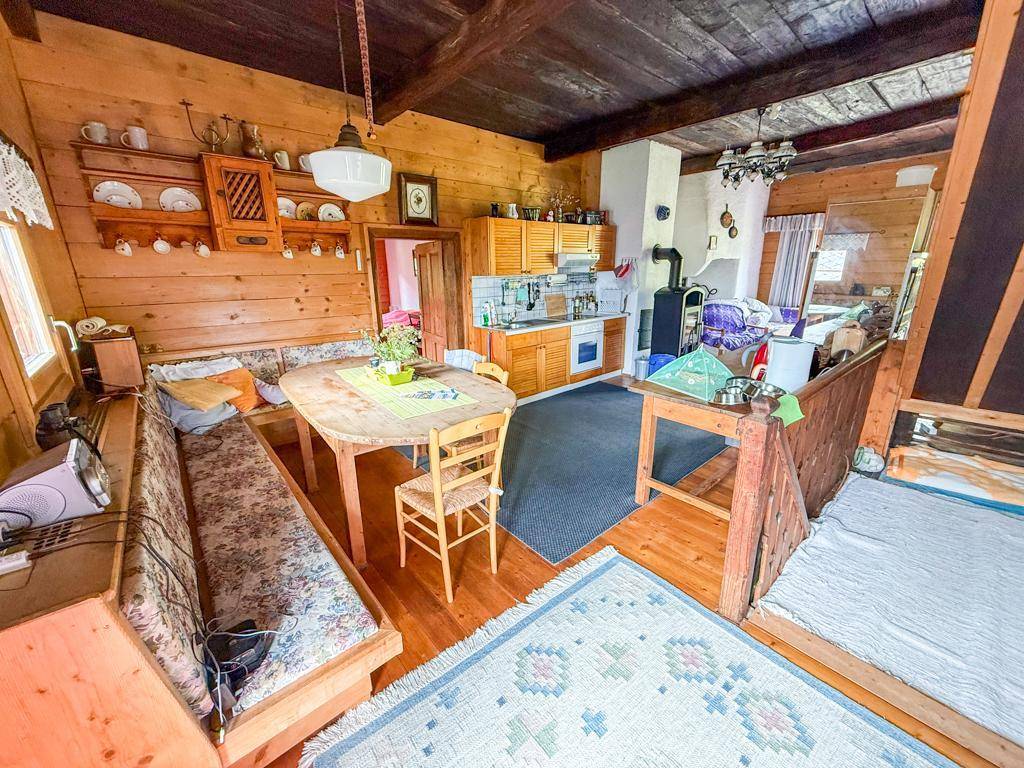 Gemütlicher offener Wohnbereich mit Holzbalken, Essplatz und kleiner Küche im traditionellen Landhausstil.