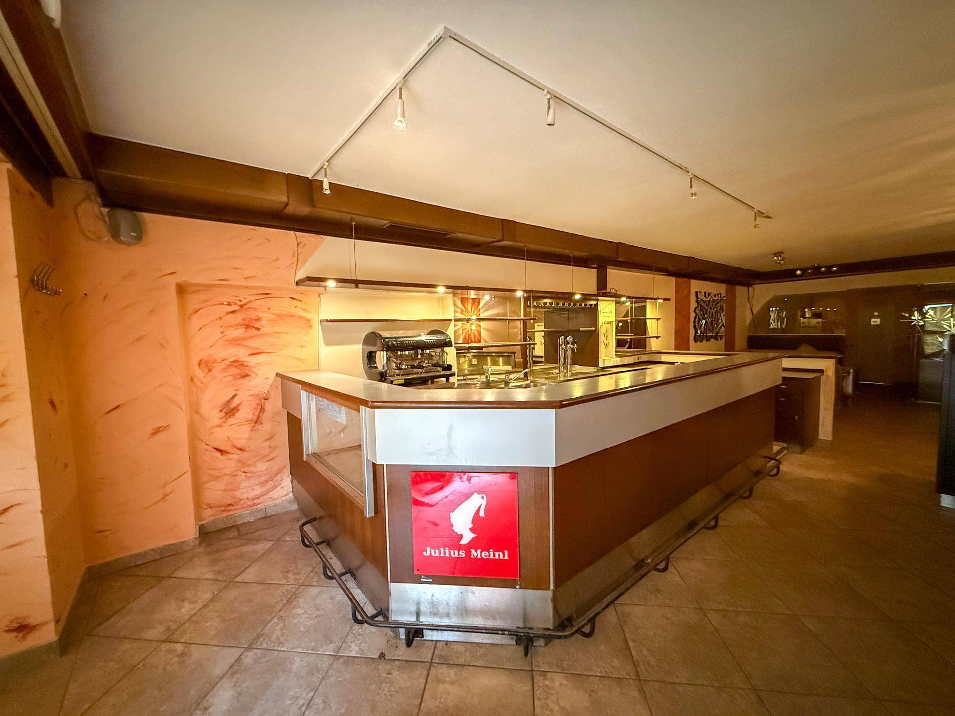 Innenansicht einer Bar mit Theke, Kaffeemaschine und gefliestem Boden in einem gewerblichen Bereich.