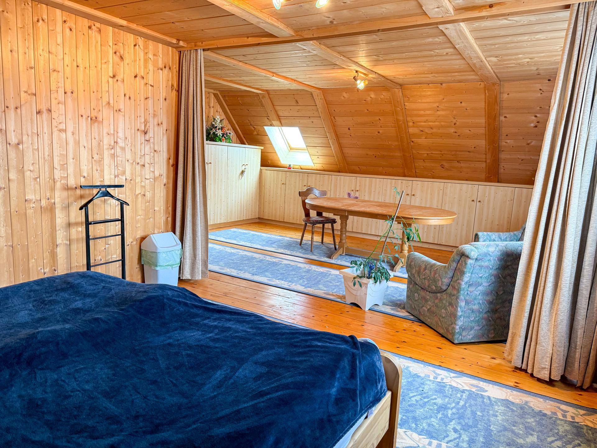 Geräumiger Schlafbereich mit integrierter Sitzecke, Holzausstattung und einem Dachfenster für natürliches Licht.