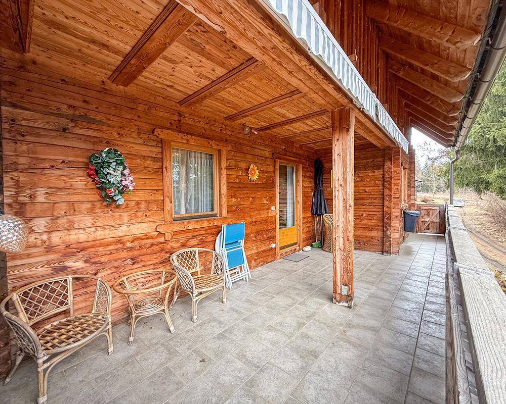 Überdachte Terrasse mit Holzwänden, Fliesenboden und Korbmöbeln, ideal für entspannte Stunden im Freien.