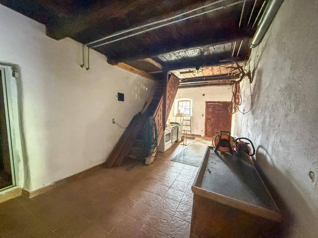 Unfertiger Raum im Untergeschoss mit Holztreppe und gefliestem Boden, als Abstellraum nutzbar.