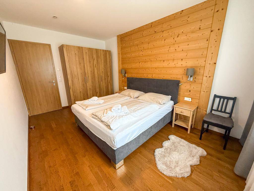 Schlafzimmer mit Holzboden, Holzwand und großem Kleiderschrank.