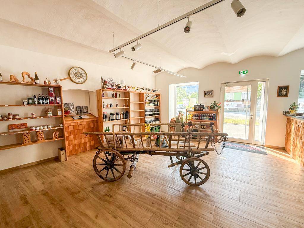 Heller Verkaufsraum mit Holzboden, gewölbter Decke und Regalen voller regionaler Produkte.