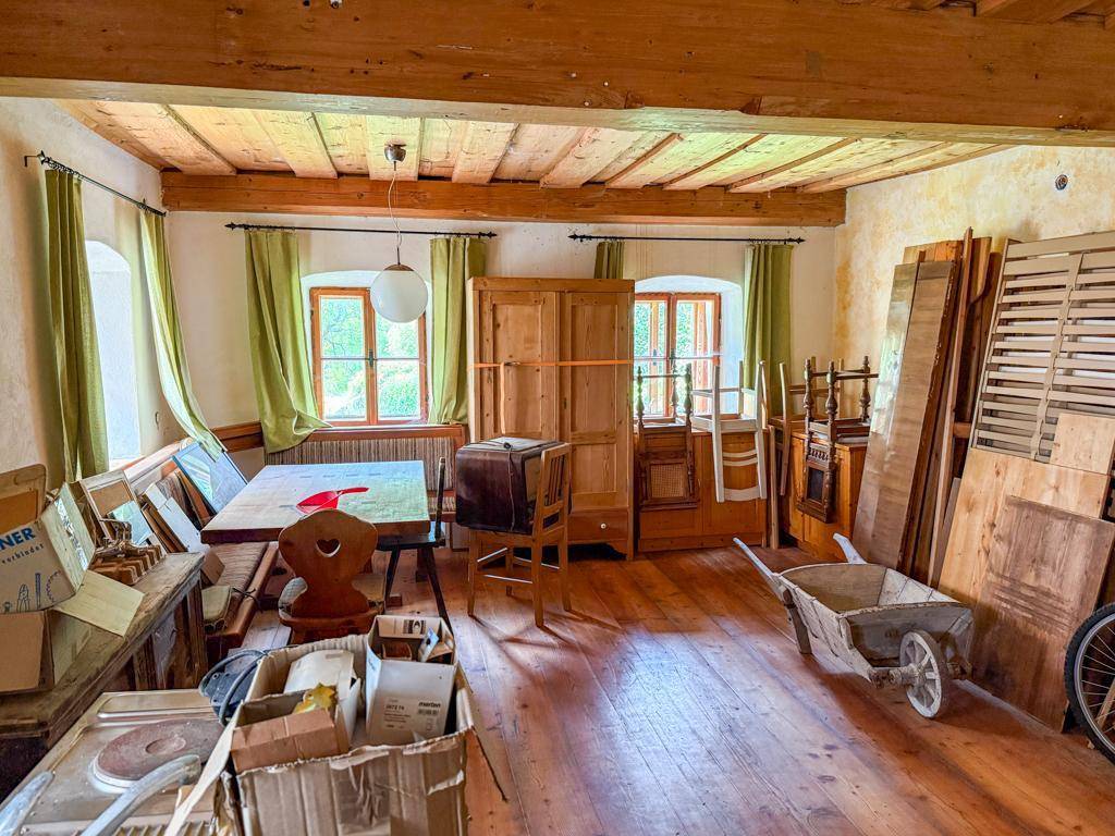Großer Raum im Obergeschoss mit Holzboden und freiliegenden Deckenbalken, als Lager genutzt.
