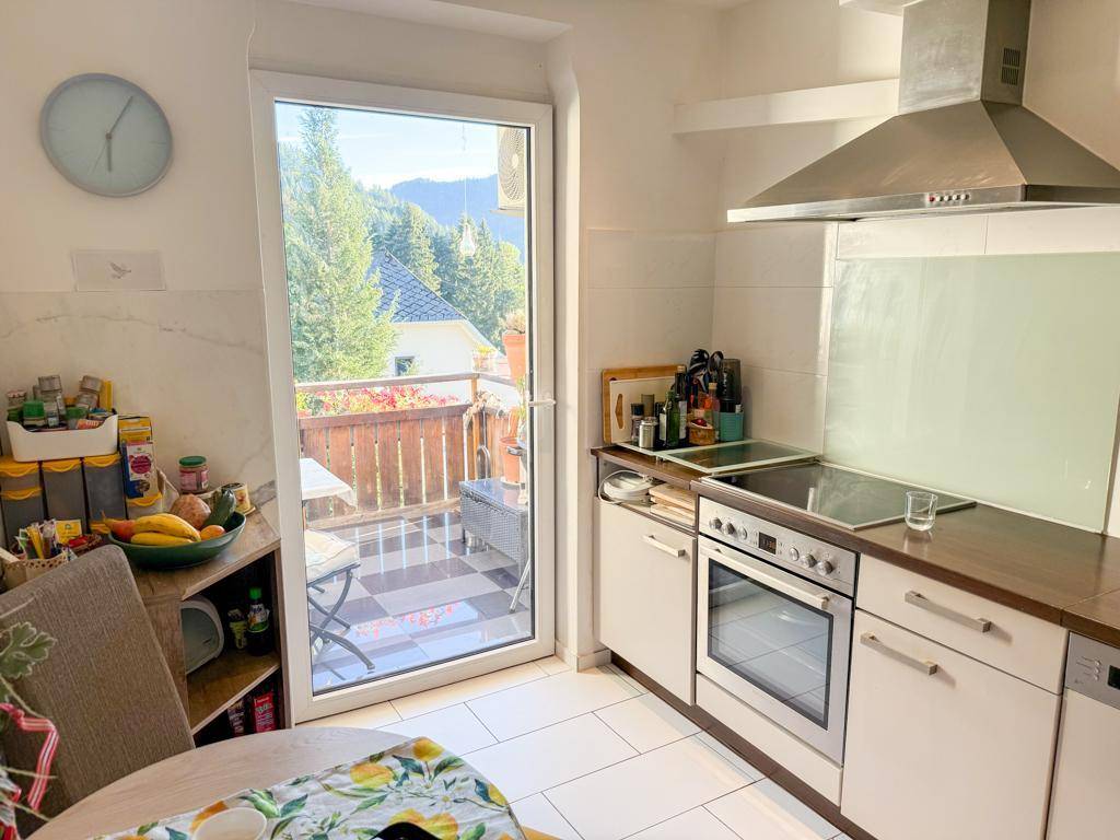 Funktionale Küche mit Einbaugeräten, Fliesenboden und direktem Zugang zum Balkon.