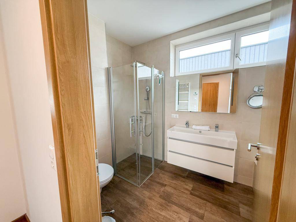 Modernes Badezimmer mit Dusche, Doppelwaschbecken und Fenster für Tageslicht.