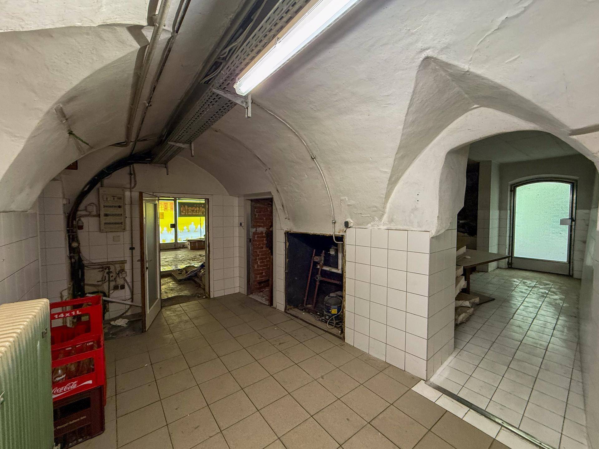 Kellerraum mit Gewölbedecken, gefliestem Boden und weißen Fliesenwänden, ideal als Lagerbereich.