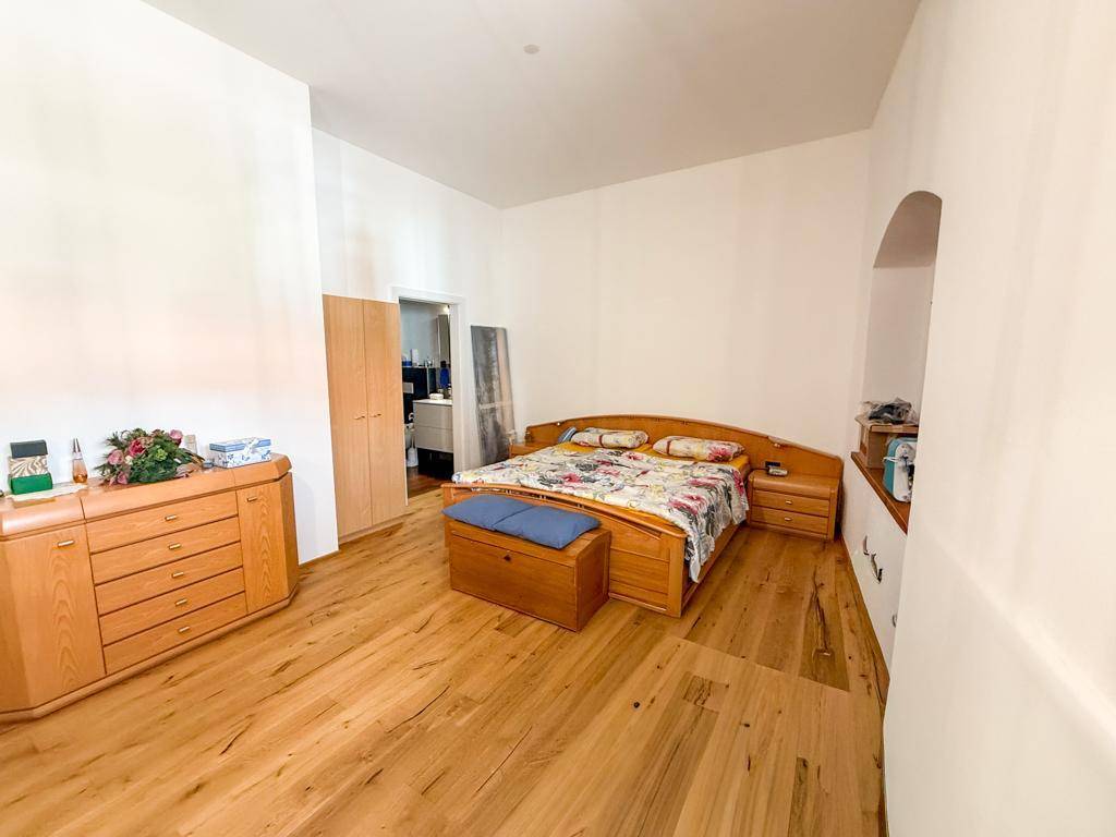 Geräumiges Schlafzimmer mit Holzbett, Kommode und hellem Holzfußboden.