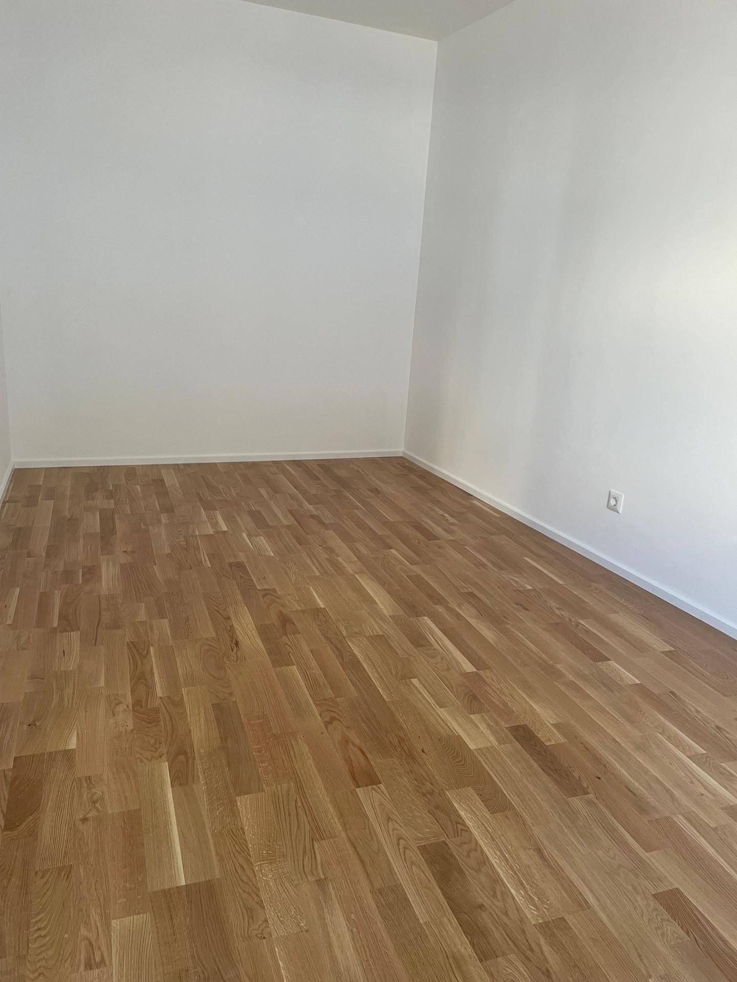 Leerer Raum mit hellem Holzboden und sauberen weißen Wänden, bereit zur Einrichtung.
