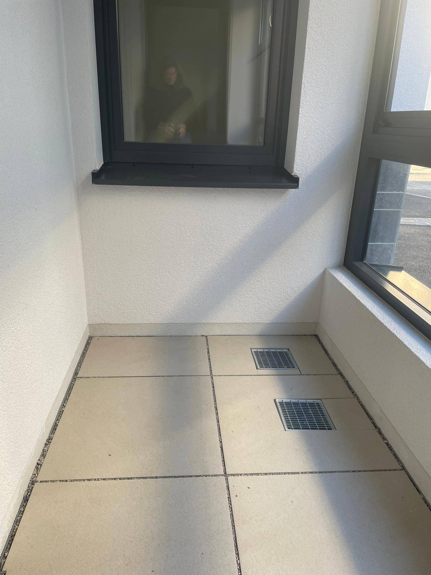 Überdachter Außenbereich mit Fliesenboden und Fenster, ideal für entspannte Stunden.