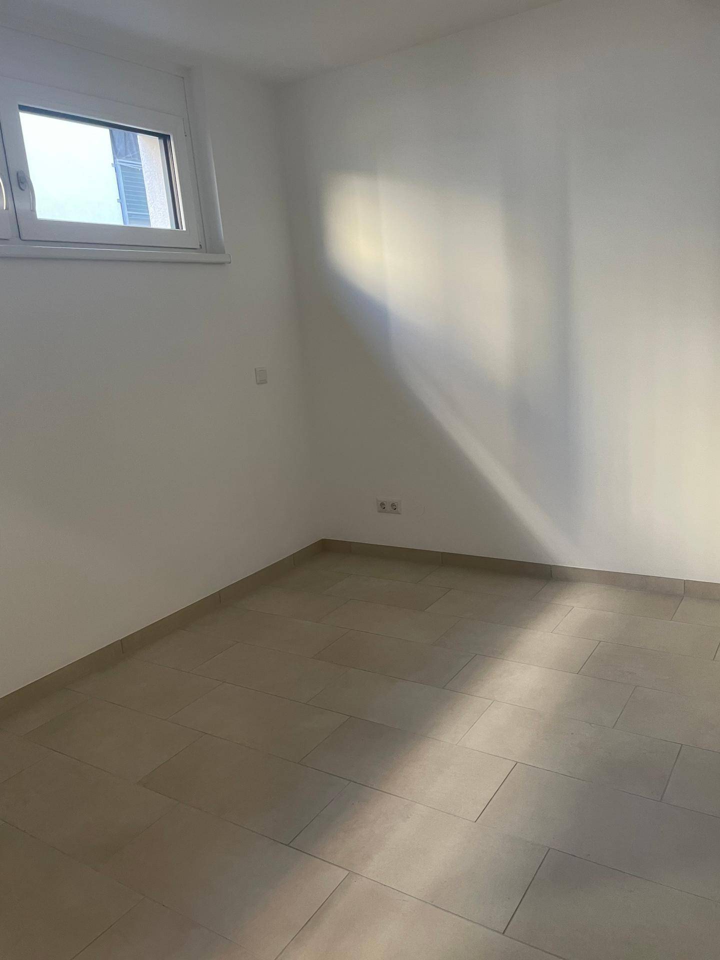 Heller Raum mit modernen Fliesen und einem Fenster, das natürliches Licht hereinlässt.